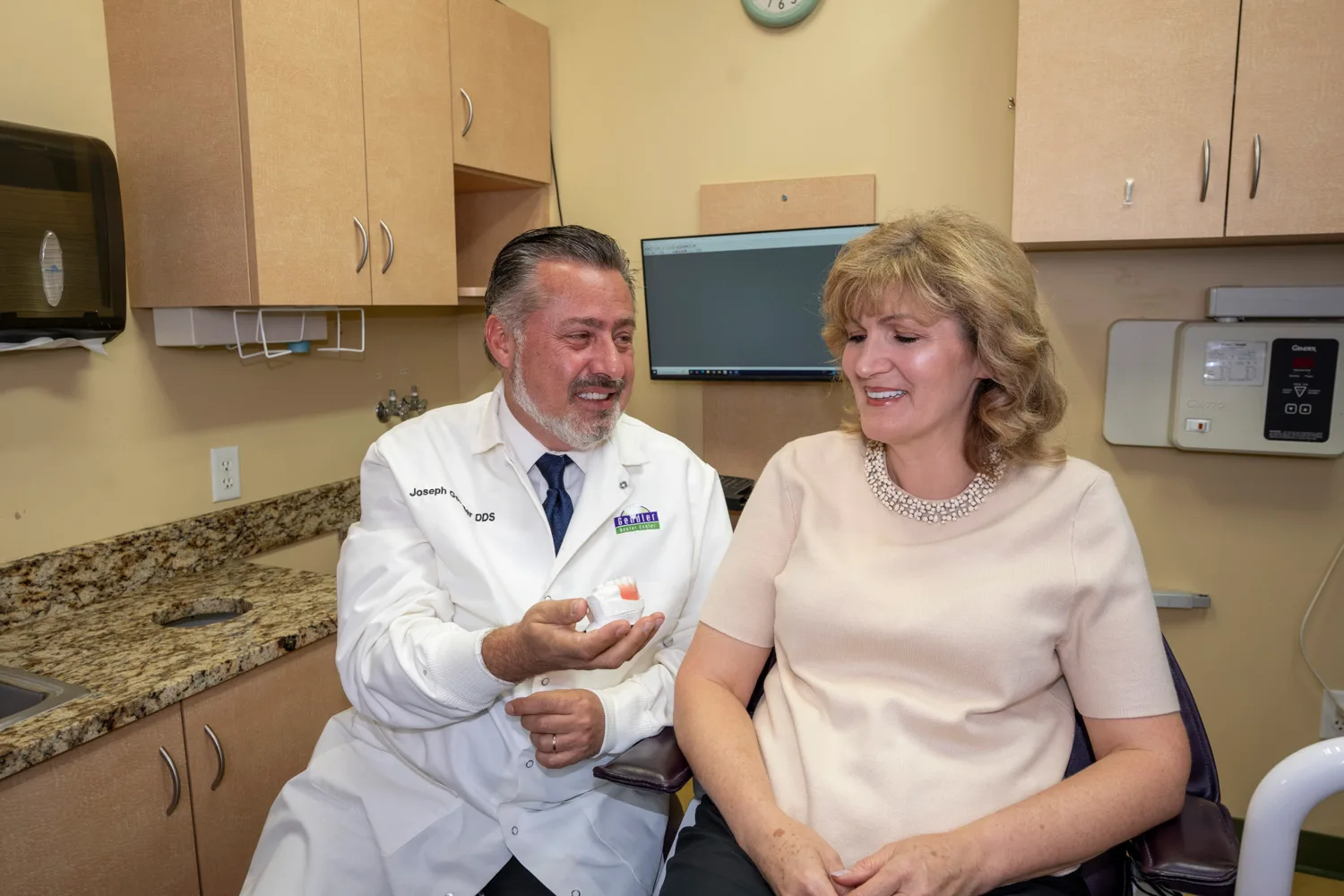 Dr. Gendler chairside with a patient, reviewing a denture model