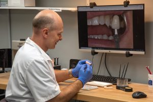 Dental lab technician makes sure denture replacement looks perfect.